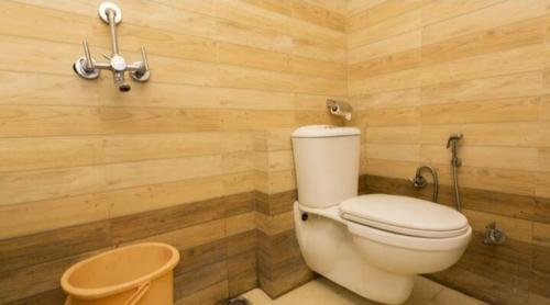 a bathroom with a toilet and a wooden wall at Hotel R DELUXE "Couple Friendly Vaccinated Staff" in New Delhi
