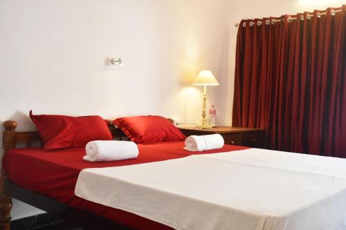 a bedroom with a bed with red pillows and a red curtain at Sky Palace Beach Hotel in Trivandrum