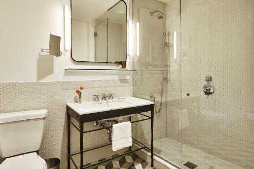 a bathroom with a sink and a glass shower at The Hollywood Roosevelt in Los Angeles