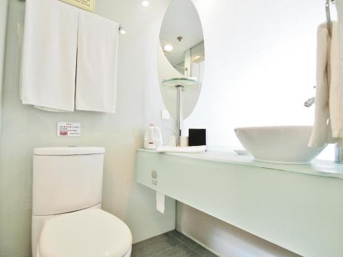 a white bathroom with a toilet and a mirror at Winland 800 Hotel - Formerly Mexan Harbour Hotel in Hong Kong