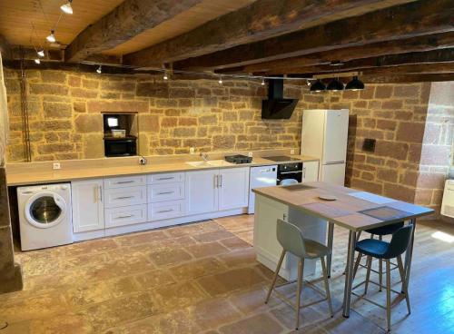 a kitchen with a sink and a table with chairs at Villa avec jaccuzi in Noailhac