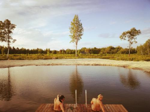 Zwei Männer sitzen auf einem Dock in einem Wasserkörper in der Unterkunft Mõiskla saun ja puhkemaja in Haapsalu