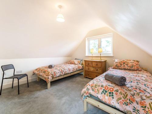 1 dormitorio con 2 camas, silla y ventana en Caldbec House Stables, en Battle