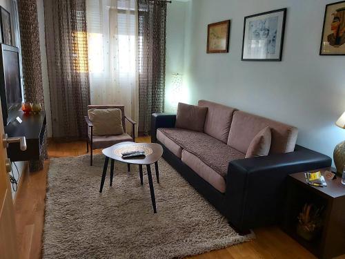 ein Wohnzimmer mit einem Sofa und einem Tisch in der Unterkunft Apartman Miss T in Podgorica