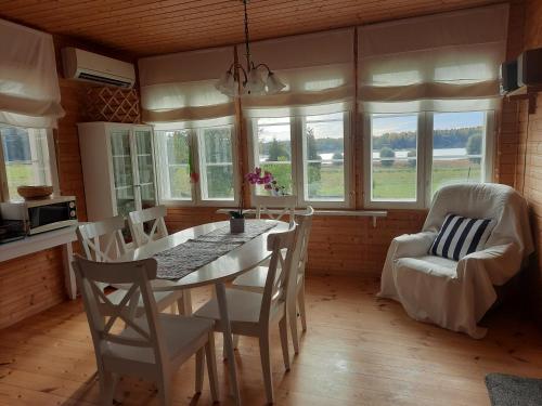 een keuken met een tafel, stoelen en ramen bij Holiday Cottage Tiira in Raseborg