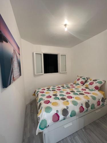 Appartement au centre de Vincennes في فينسين: غرفة نوم صغيرة مع سرير مع لحاف ملون