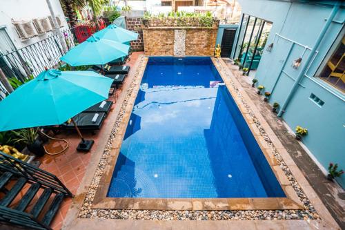 a swimming pool with two blue umbrellas next to it at The Rabbit Hole Hotel & SPA in Siem Reap
