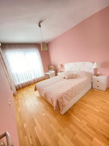 różowa sypialnia z łóżkiem i drewnianą podłogą w obiekcie Molly's Suite w mieście Sofia