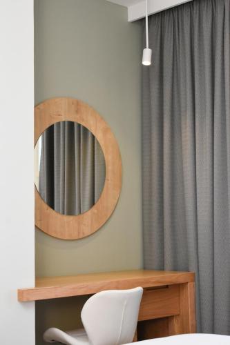 a mirror on a wall next to a white chair at Elena Village Hotel & Suites in Kalymnos
