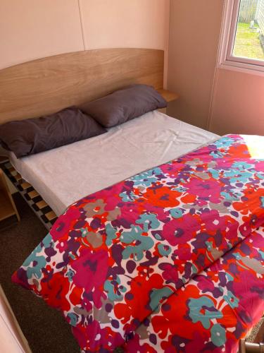 a bedroom with a bed with a colorful comforter at 707 Seawick in Jaywick Sands