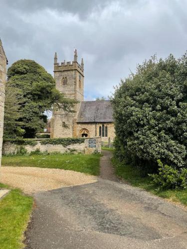 an old stone church with a tower in the distance at Honey Cottage, Halford (Annex cottage) in Halford