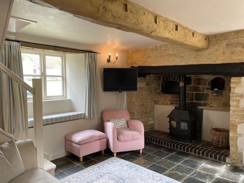 a living room with a fireplace and a pink chair at Honey Cottage, Halford (Annex cottage) in Halford