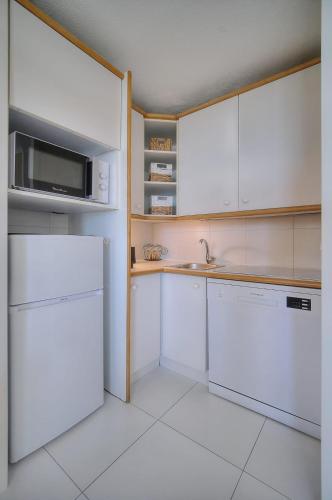 une cuisine avec des armoires blanches, un évier et un réfrigérateur dans l'établissement IMMOGROOM - Renovated - Sea view - Pool - Patio - Wifi - AC - Parking, à Cannes