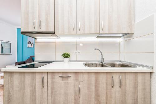 a kitchen with wooden cabinets and a sink at Lovely apartment Taidia in Maspalomas