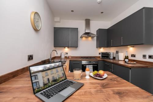 a laptop computer sitting on a wooden table in a kitchen at The Croston promenade balcony apartment- Morecambe central promenade, beach front and sea views in Morecambe