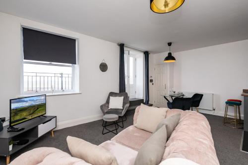 a living room with a couch and a tv at The Croston promenade balcony apartment- Morecambe central promenade, beach front and sea views in Morecambe