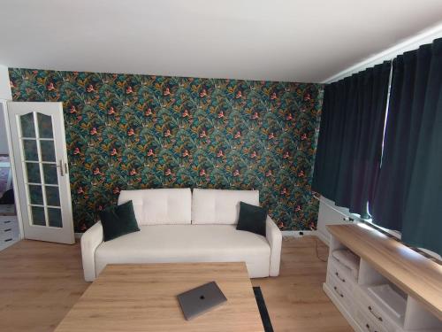 sala de estar con sofá blanco y papel pintado con motivos florales en Gdynia Apartment, en Gdynia