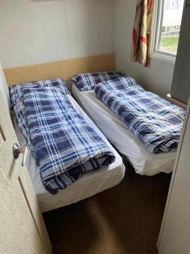 two beds in a small room with a window at 617 seawick in Jaywick Sands