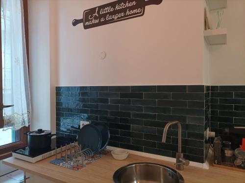um balcão de cozinha com um lavatório e uma parede de azulejos pretos em DomuSumma em Roma