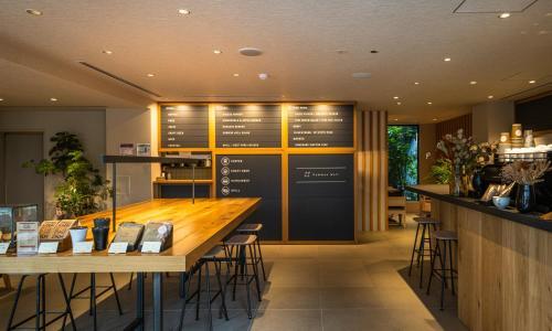 a restaurant with a long bar with tables and stools at HOTEL RINGS KYOTO in Kyoto