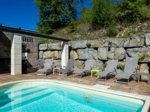 une piscine avec des chaises longues et un mur en pierre dans l'établissement Impasse des Faysses, à Ruoms