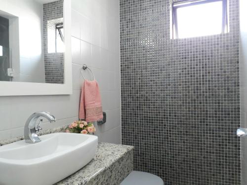 ein Bad mit einem Waschbecken und einer Dusche in der Unterkunft Conforto a 300m da Praia do Forte in Cabo Frio
