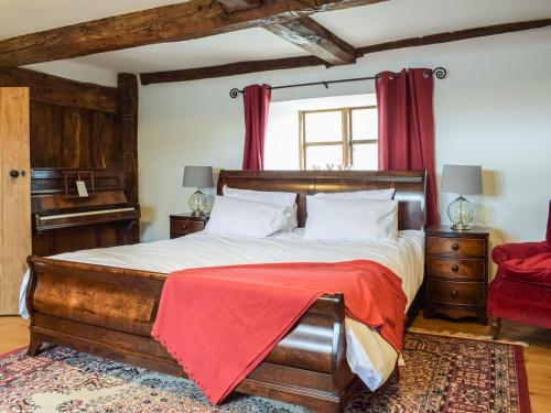 a bedroom with a wooden bed with a red blanket on it at Colstey Farmhouse in Acton