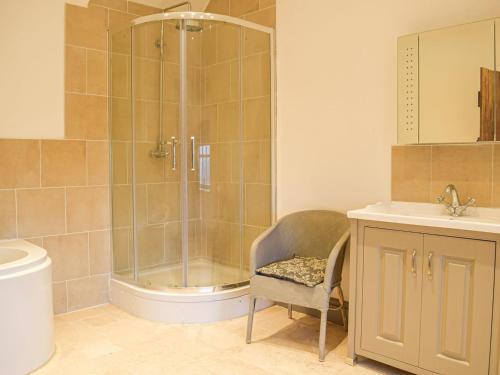 a bathroom with a shower and a chair and a sink at Colstey Farmhouse in Acton