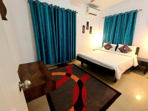 a bedroom with a bed with blue curtains and a rug at Siolim 6bhk Private Villa with Private Pool close to Anjuna Vagator in Siolim