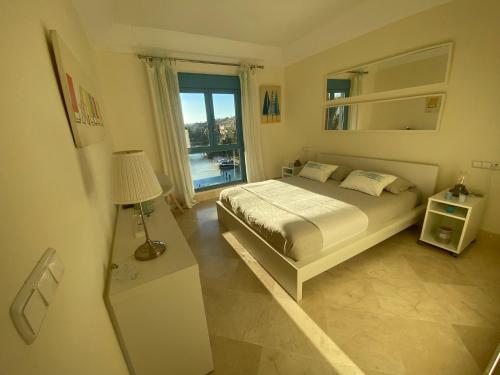 1 dormitorio con cama y ventana grande en Apartamento con terraza sobre La Marina de Sotogrande, en San Roque
