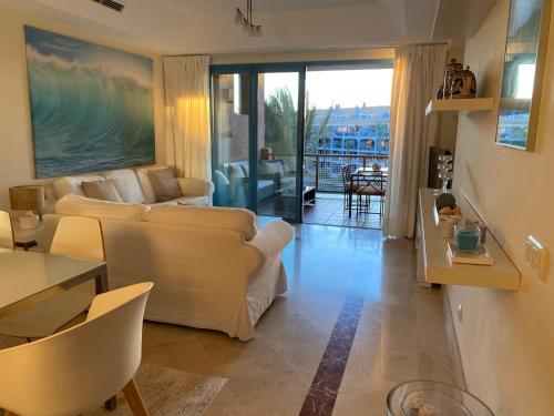 sala de estar con muebles blancos y ventana grande en Apartamento con terraza sobre La Marina de Sotogrande, en San Roque