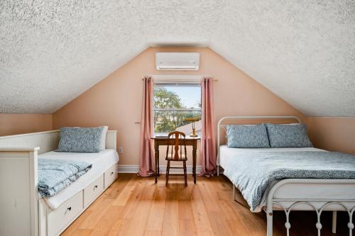 a attic bedroom with two beds and a table at Sunroom on Maple in Picton