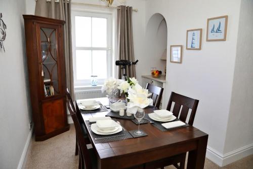 a dining room table with plates and flowers on it at Finest Retreats - Glendale in Skinburness