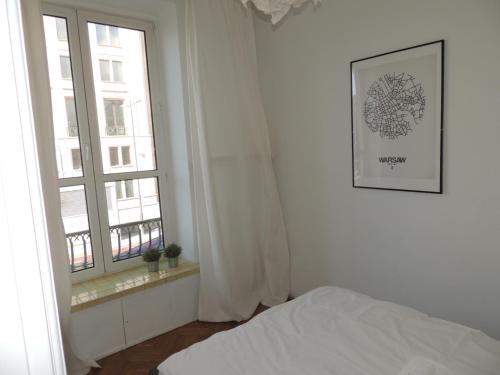 um quarto branco com uma cama e uma janela em Apartament Warecka em Varsóvia