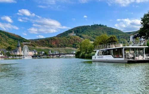 a boat on a river with mountains in the background at KL Moselboote - Hausboot Niara in Bernkastel-Kues
