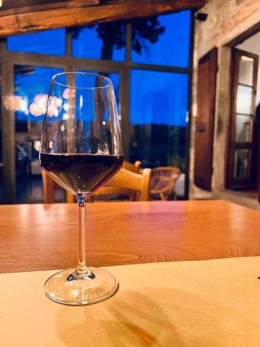 a glass of wine sitting on a wooden table at LOCANDA PODERE LE VIGNE in Radda in Chianti