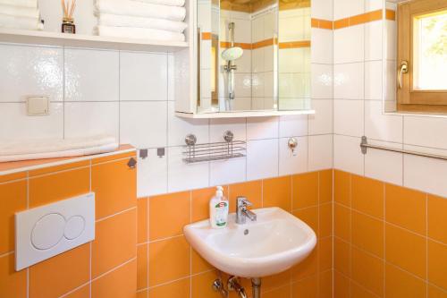 pomarańczowa i biała łazienka z umywalką i lustrem w obiekcie Kellerstöckl Postrumer Weinberg 48 w mieście Kulm im Burgenland