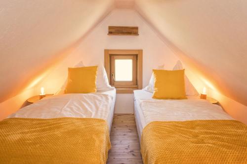 2 Betten mit gelben Kissen in einem Dachzimmer in der Unterkunft Kellerstöckl Postrumer Weinberg 48 in Kulm im Burgenland