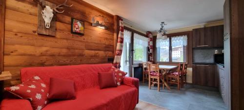 salon z czerwoną kanapą i stołem w obiekcie Baita del Cervino CIR n 0016 w mieście Breuil-Cervinia