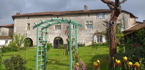 a building with a green arch in front of a yard at Chambre Renaissance au Château de Champagne-Mouton in Champagne-Mouton