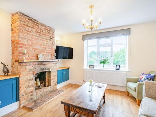 a living room with a brick fireplace and a table at Stonegarth in Snitterby