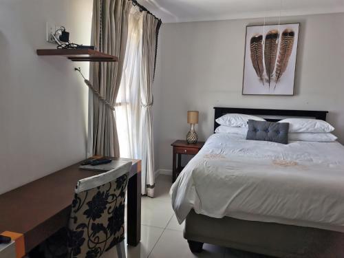 a bedroom with a bed and a table and a window at Blouberg Manor in Bloubergstrand