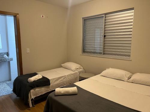 a room with two beds and a window at Locking´s Santo Agostinho 5 - Apto 2 quartos 2 vagas novo in Belo Horizonte