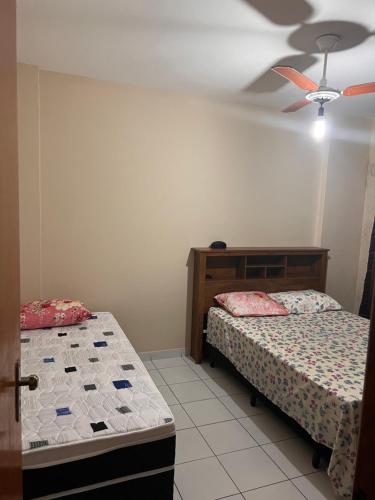 a bedroom with two beds and a ceiling fan at Residencial Michelângelo in Mongaguá