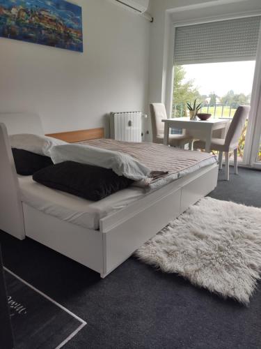 - un lit blanc dans une chambre avec une table et des chaises dans l'établissement Studio apartment "Iris", à Ptuj