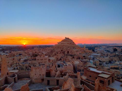 una puesta de sol sobre una ciudad con una pirámide en el fondo en Hidigda Camp, en ‘Izbat Ţanāţī