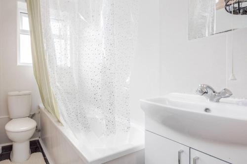 a white bathroom with a toilet and a sink at Impeccable and welcoming 3-Bed House in London in London