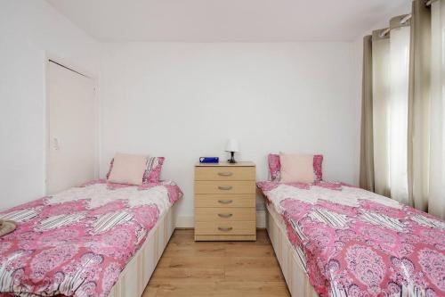 two beds sitting next to each other in a bedroom at Impeccable and welcoming 3-Bed House in London in London