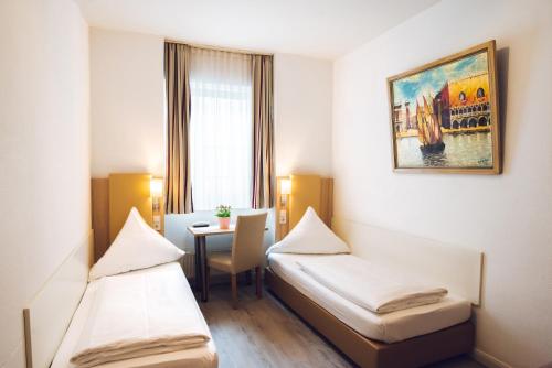 a room with two beds and a table in it at Hotel Domblick Garni in Cologne