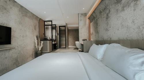 um quarto com uma grande cama branca num quarto em The Cara Boutique Hotel em Kota Kinabalu